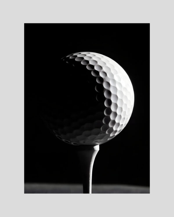 Affiche en noir et blanc d’une balle de golf éclairée fortement sur fond noir, style artistique et minimaliste