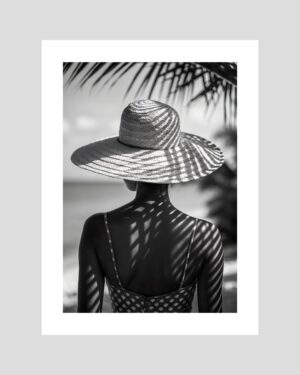 Femme de dos à la plage avec chapeau de paille, jeux d’ombre – affiche noir et blanc style tropical