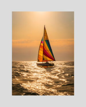 Affiche d’un voilier coloré naviguant au coucher du soleil sur une mer calme et dorée